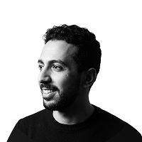 Portrait of a man with short curly hair and a beard looking left, wearing a black shirt.